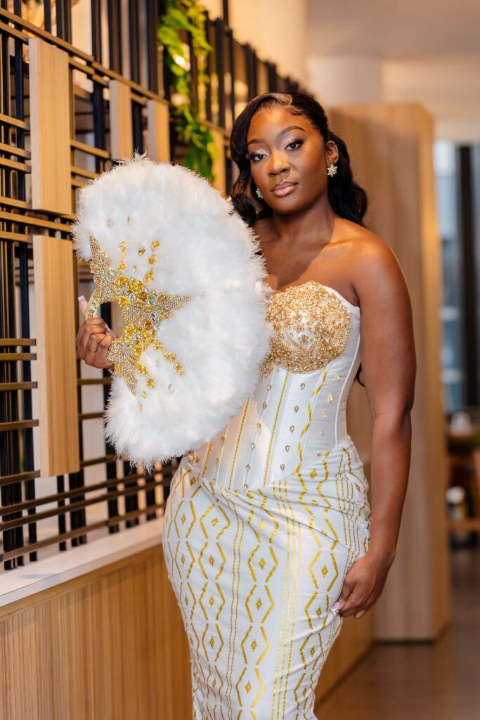 Mariée en robe traditionnelle blanche et or avec éventail