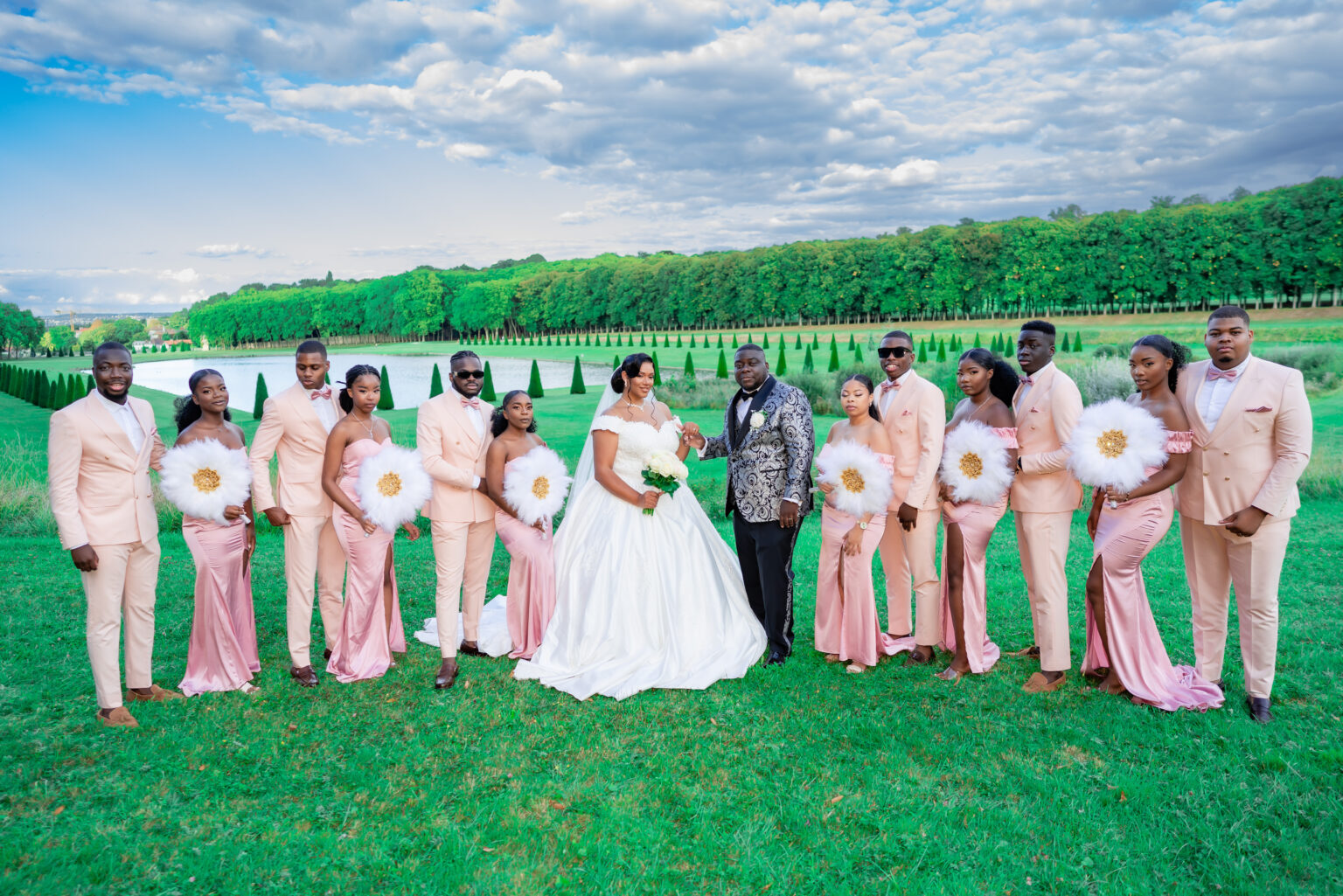 Cortège de mariage en tenues roses autour des mariés sur une pelouse
