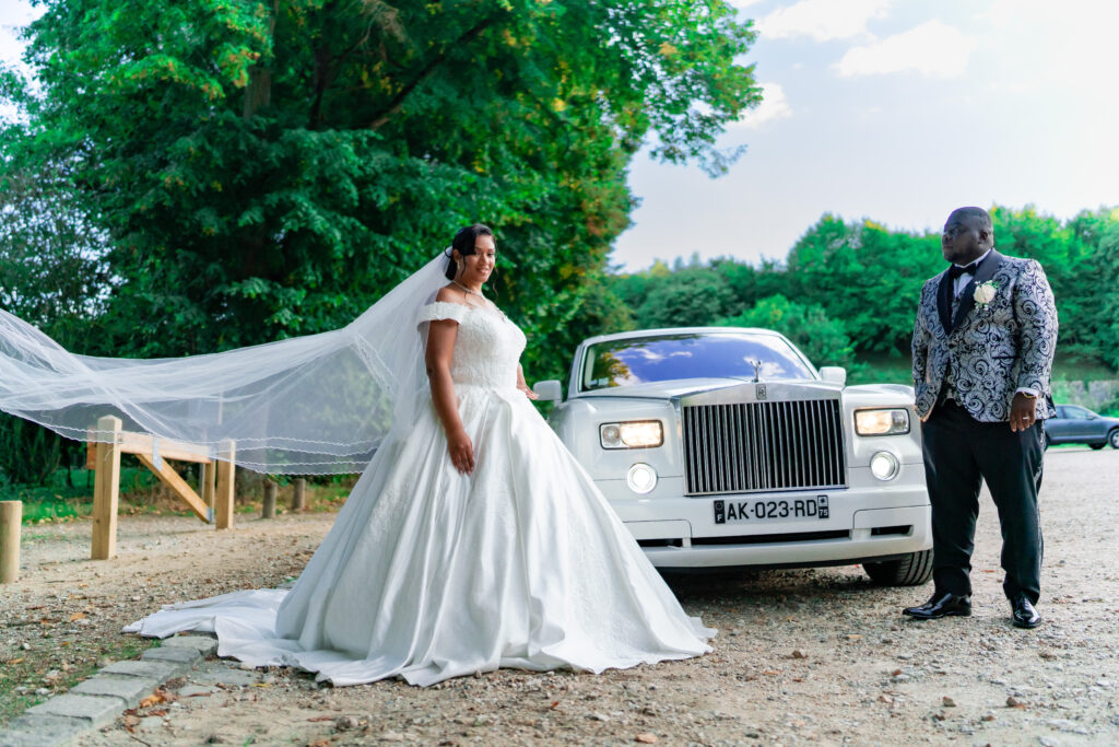 Mariée au voile flottant devant une Rolls-Royce blanche