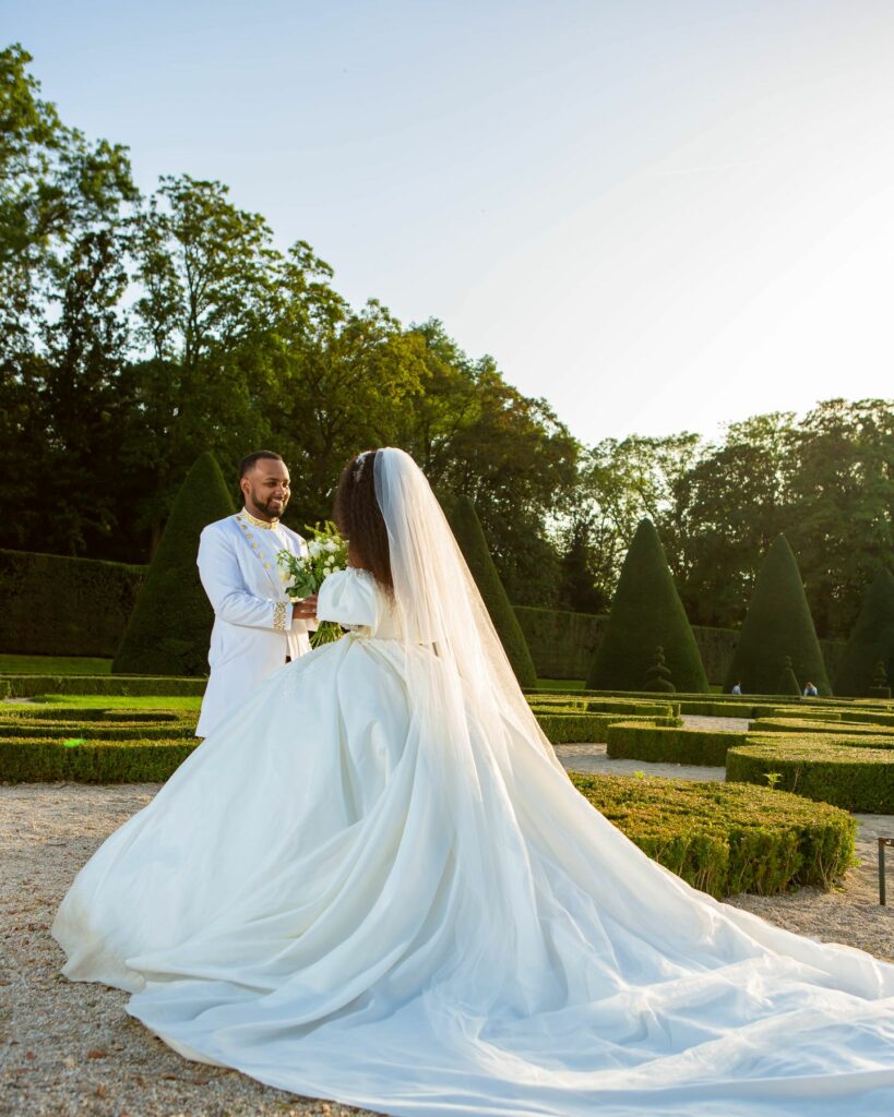 Mariée dans un parc au coucher du soleil, longue traîne sur l'herbe